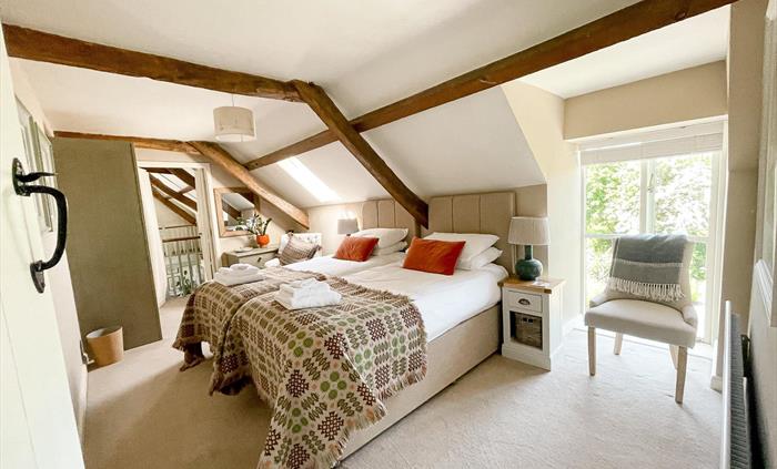 Twin beds in the east wing bedroom at the seadog and stone self catering holiday let ysgubor degwm. Welsh blankets in brown and green with orange thro